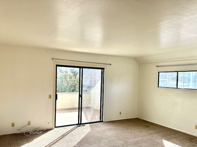 unfurnished room with a wealth of natural light, carpet floors, a textured ceiling, and lofted ceiling