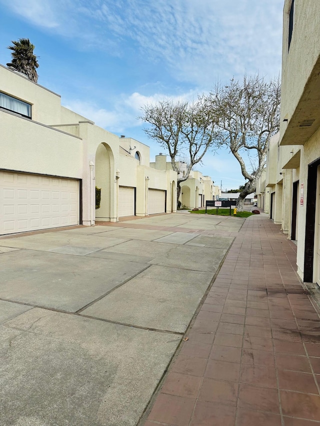 exterior space with community garages, a residential view, and stucco siding