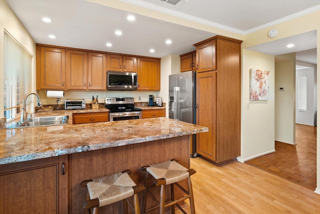 kitchen featuring light stone counters, appliances with stainless steel finishes, a peninsula, and a sink