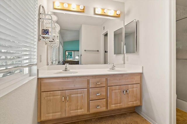 full bathroom with double vanity, vaulted ceiling, baseboards, and a sink