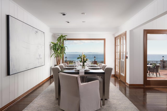 dining room with plenty of natural light, baseboards, dark wood-style flooring, and a water view