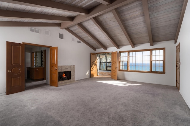 unfurnished living room featuring beam ceiling, visible vents, carpet, and a lit fireplace