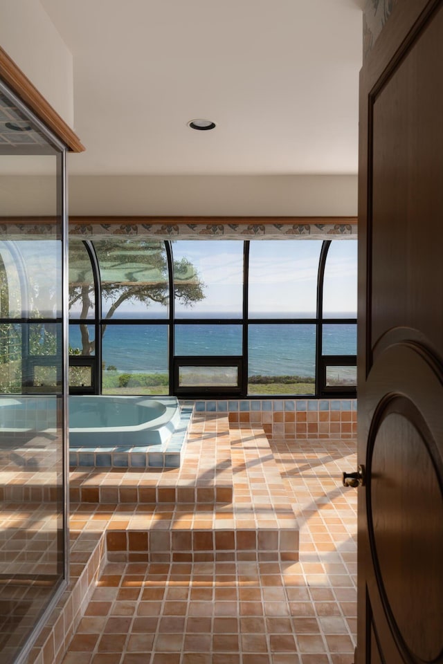 bathroom with tiled bath and a water view