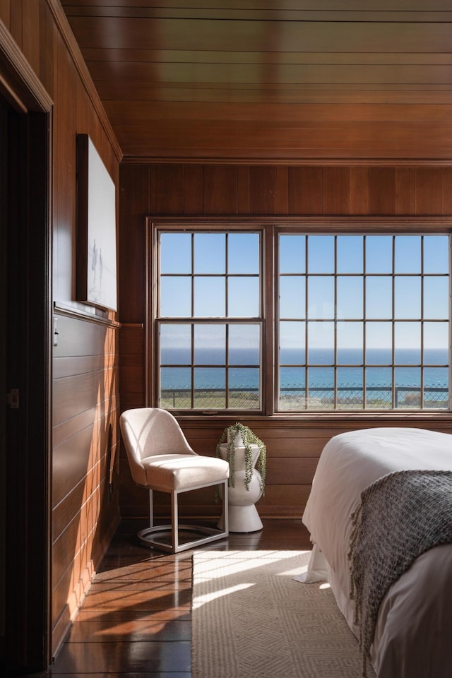 bedroom featuring wood walls, multiple windows, and a water view