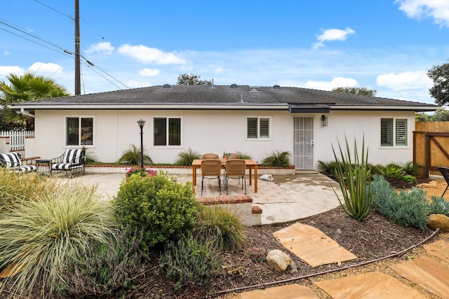 rear view of property with stucco siding, fence, and a patio area