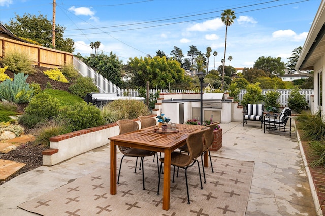 view of patio / terrace featuring exterior kitchen, outdoor dining area, and a fenced backyard