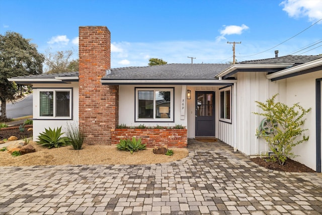 doorway to property with board and batten siding and a shingled roof