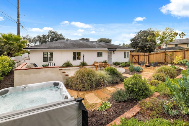 back of house featuring stucco siding, a patio, a fenced backyard, and a hot tub