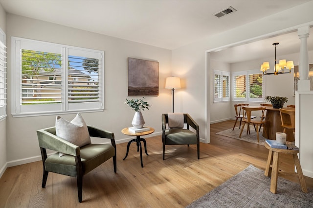 living area featuring an inviting chandelier, baseboards, visible vents, and light wood finished floors