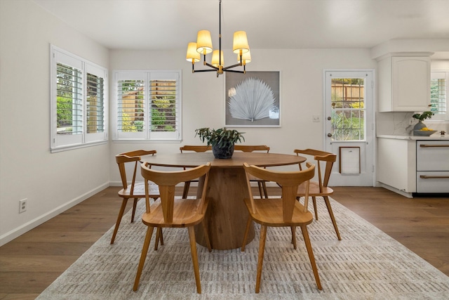 dining area featuring a notable chandelier, wood finished floors, and baseboards