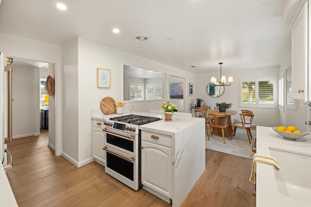 kitchen with a chandelier, double oven range, light wood-type flooring, a peninsula, and white cabinets