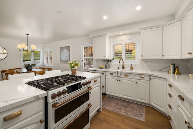 kitchen featuring light wood-style flooring, a sink, double oven range, light stone counters, and an inviting chandelier