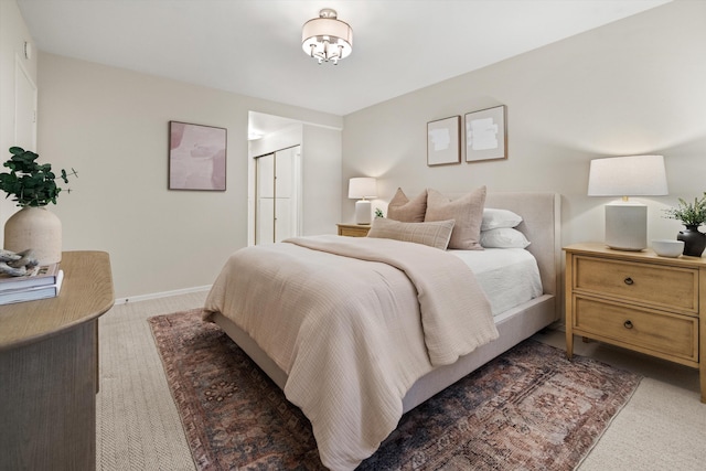 bedroom featuring light colored carpet, baseboards, and a closet