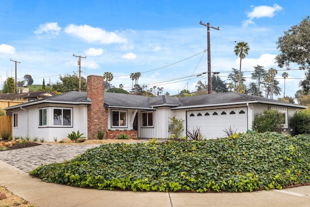 ranch-style house with a chimney, a garage, and stucco siding