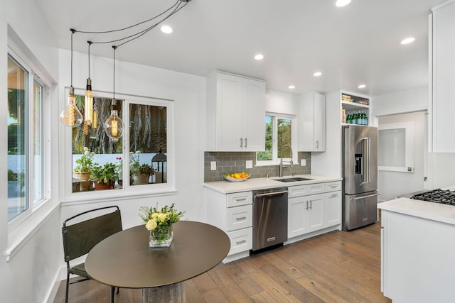 kitchen with a sink, dark wood-type flooring, light countertops, appliances with stainless steel finishes, and tasteful backsplash