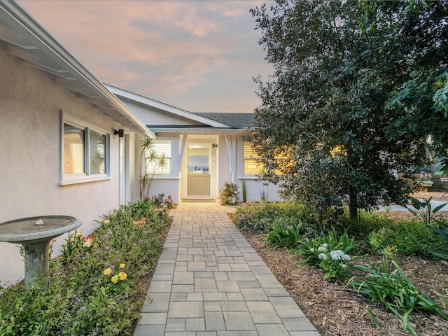 property entrance featuring a shingled roof and stucco siding