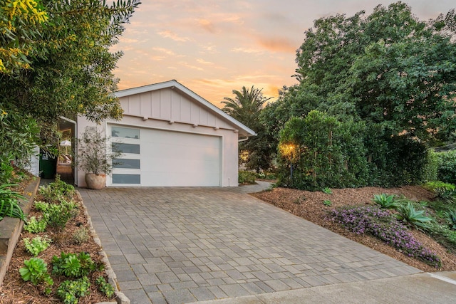 garage at dusk featuring decorative driveway