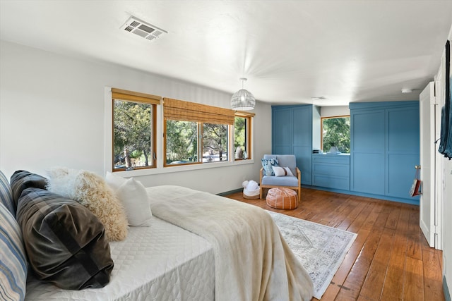 bedroom featuring hardwood / wood-style floors, multiple windows, and visible vents