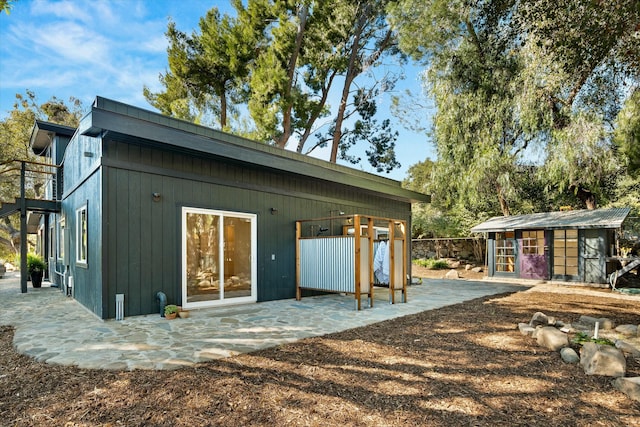 back of property featuring a storage shed, an outdoor structure, and a patio