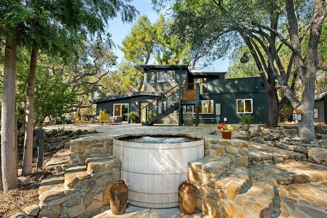 back of house featuring stairway, a jacuzzi, and a patio area