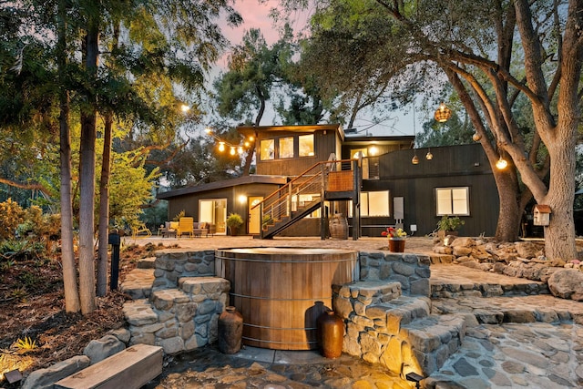 back of property featuring a jacuzzi, stairs, and a patio area