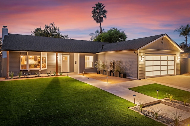 view of front of home with a front yard, concrete driveway, a garage, and roof with shingles