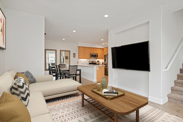 living area featuring recessed lighting, stairway, baseboards, and light wood finished floors