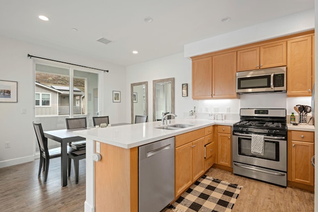 kitchen featuring visible vents, light countertops, appliances with stainless steel finishes, a peninsula, and a sink