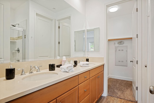 full bath featuring double vanity, wood finished floors, a stall shower, and a sink