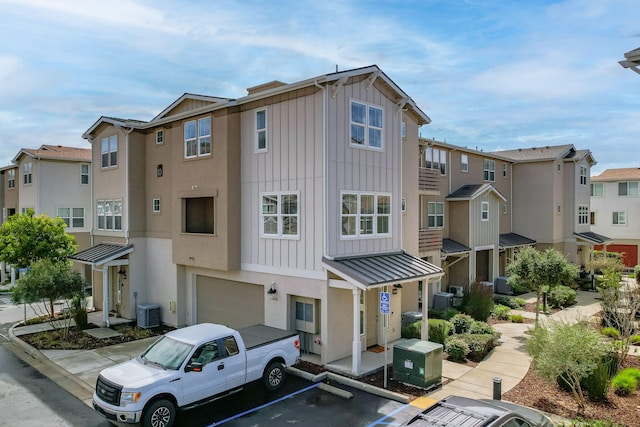 view of building exterior with a residential view, central air condition unit, an attached garage, and uncovered parking