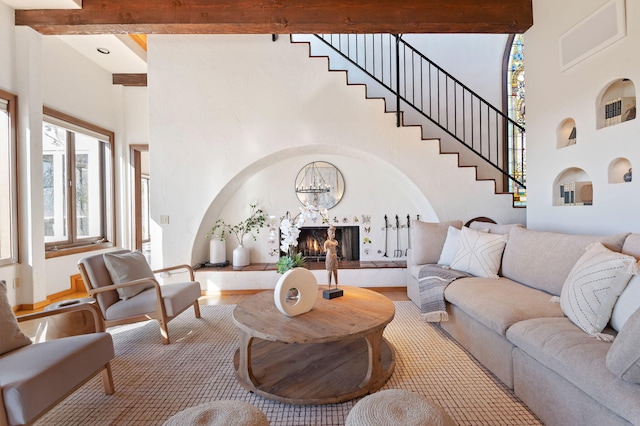 living room with beam ceiling, a high ceiling, and a high end fireplace