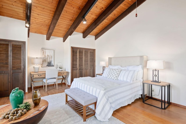 bedroom with beam ceiling, two closets, wood finished floors, wooden ceiling, and baseboards