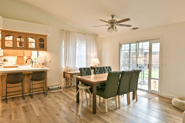 dining space featuring visible vents, baseboards, light wood-style floors, lofted ceiling, and ceiling fan