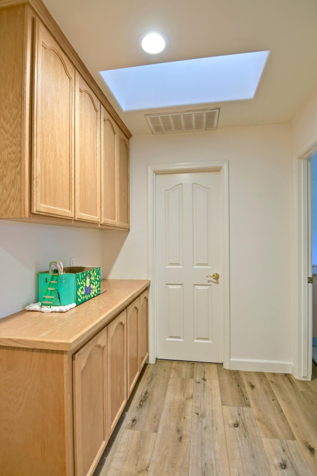 clothes washing area with visible vents and light wood-style flooring