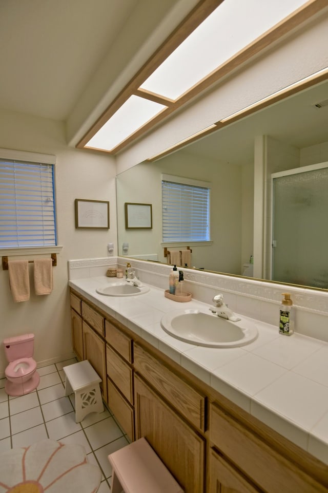 full bathroom featuring a sink, a stall shower, double vanity, and tile patterned flooring