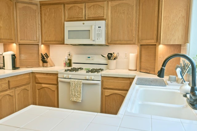 kitchen featuring white appliances, tile countertops, tasteful backsplash, and a sink