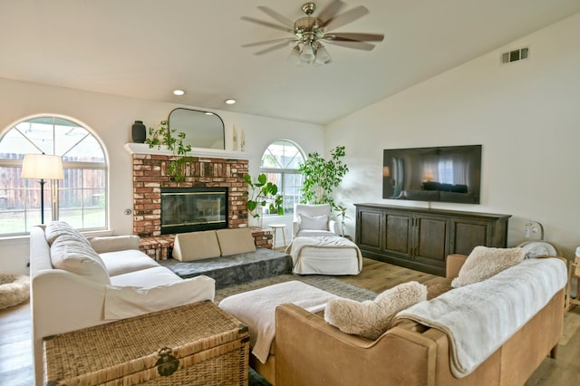 living area featuring visible vents, lofted ceiling, a healthy amount of sunlight, and wood finished floors