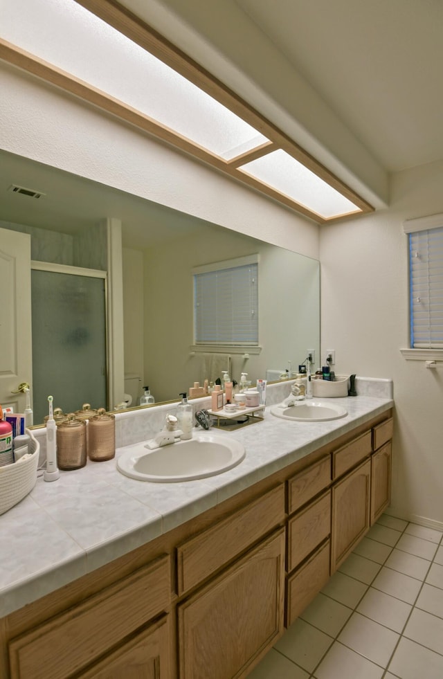 full bath with tile patterned floors, a stall shower, visible vents, and a sink