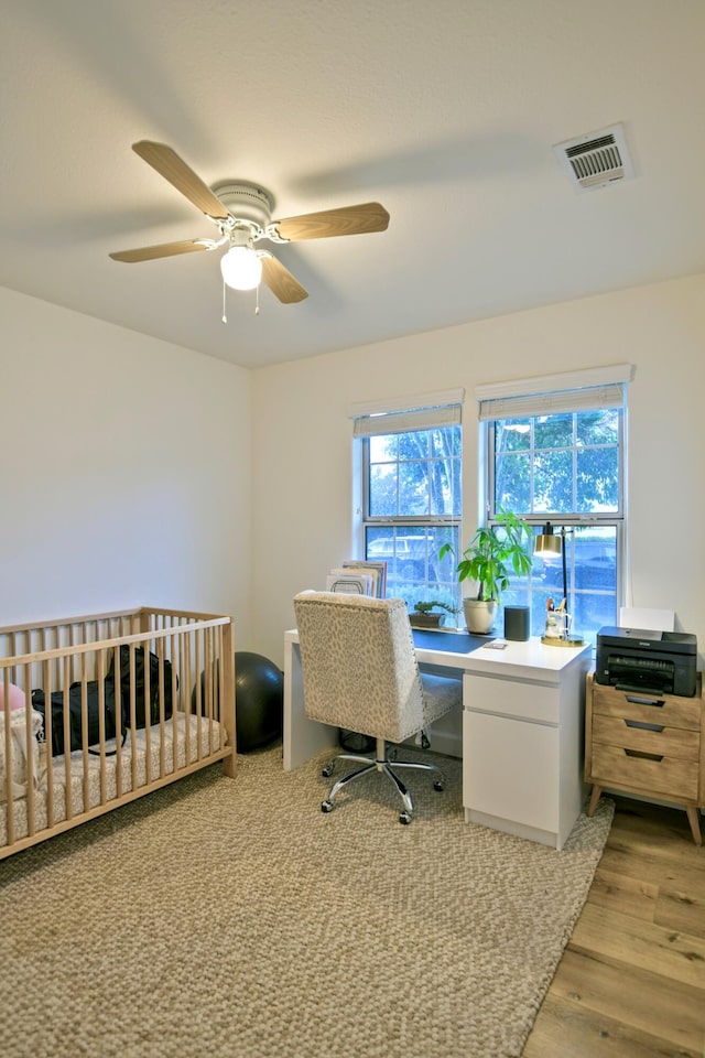 bedroom with ceiling fan, a nursery area, visible vents, and light wood-type flooring