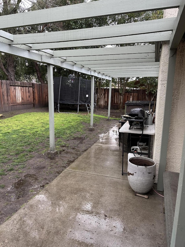 view of car parking with a trampoline and a fenced backyard