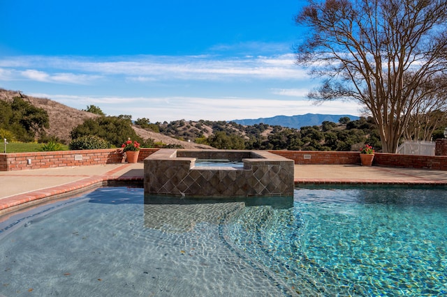 view of pool featuring a mountain view, an in ground hot tub, and a patio