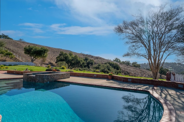 view of pool featuring a patio area, a mountain view, and a pool with connected hot tub