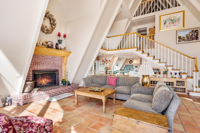 tiled living area with a fireplace, high vaulted ceiling, and stairs