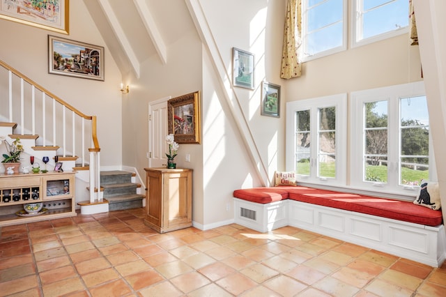 foyer featuring visible vents, beam ceiling, high vaulted ceiling, stairway, and baseboards