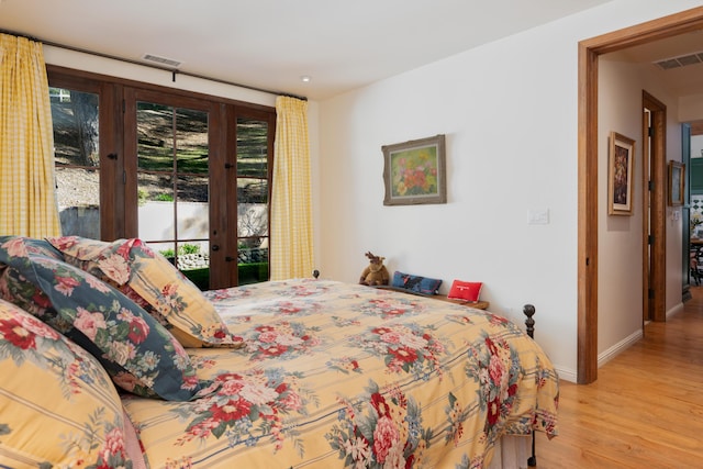 bedroom with wood finished floors, access to outside, french doors, and visible vents