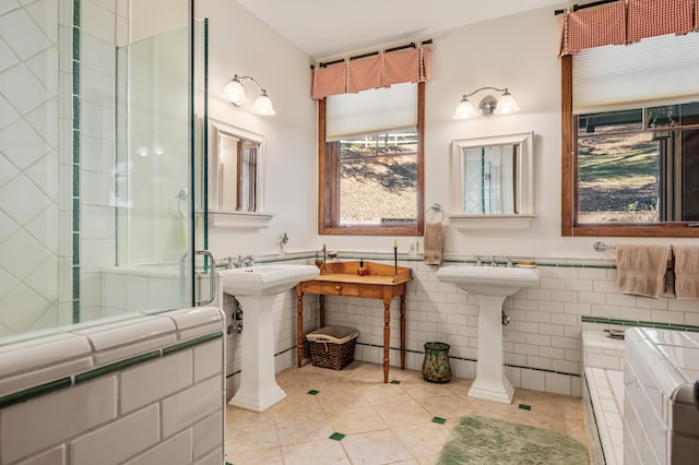 bathroom with a shower with door, a wainscoted wall, tile walls, and tile patterned flooring