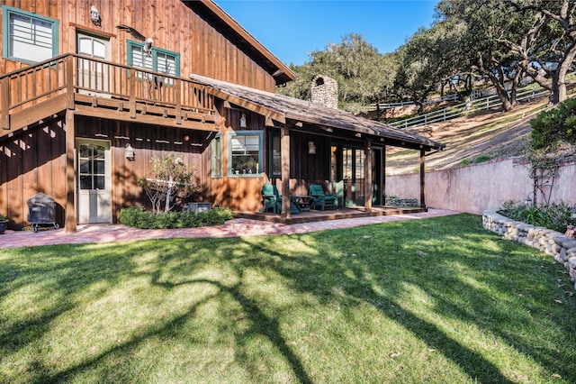 back of house featuring a patio area, a chimney, a yard, and fence