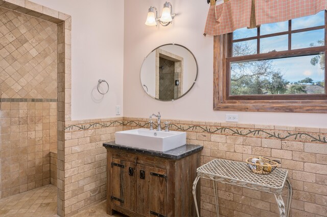 full bathroom featuring vanity, tile walls, a wainscoted wall, and a tile shower