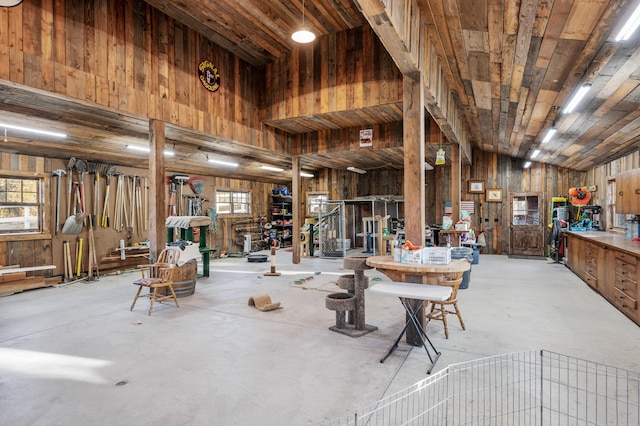 misc room with a wealth of natural light, wooden walls, concrete flooring, and lofted ceiling