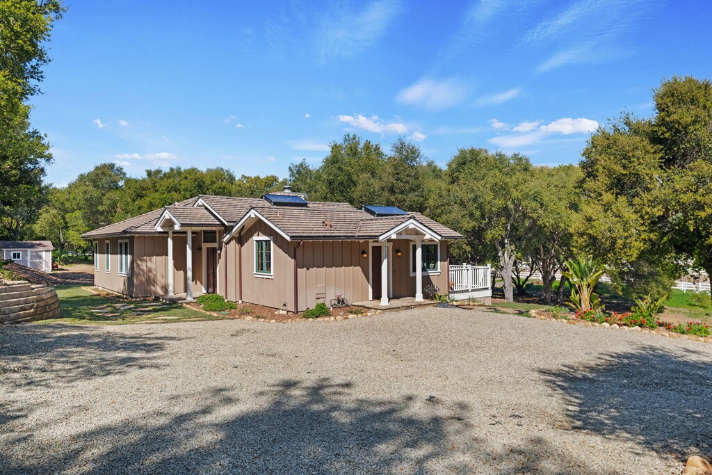 7130 Gobernador Canyon Rd, Carpinteria, CA 93013 - view of front of home featuring a wooden deck, a tiled roof, roof mounted solar panels, board and batten siding, and driveway